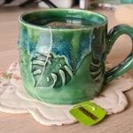 a green tea mug with monstera leaves in the ceramic