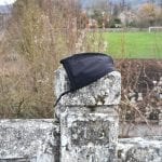 a face mask discarded on a stone fence above train tracks