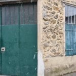 snowflakes falling in front of a green garage door and stone building