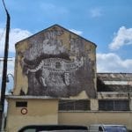 a building with a mural of a cat with a cage body and a dove flying out