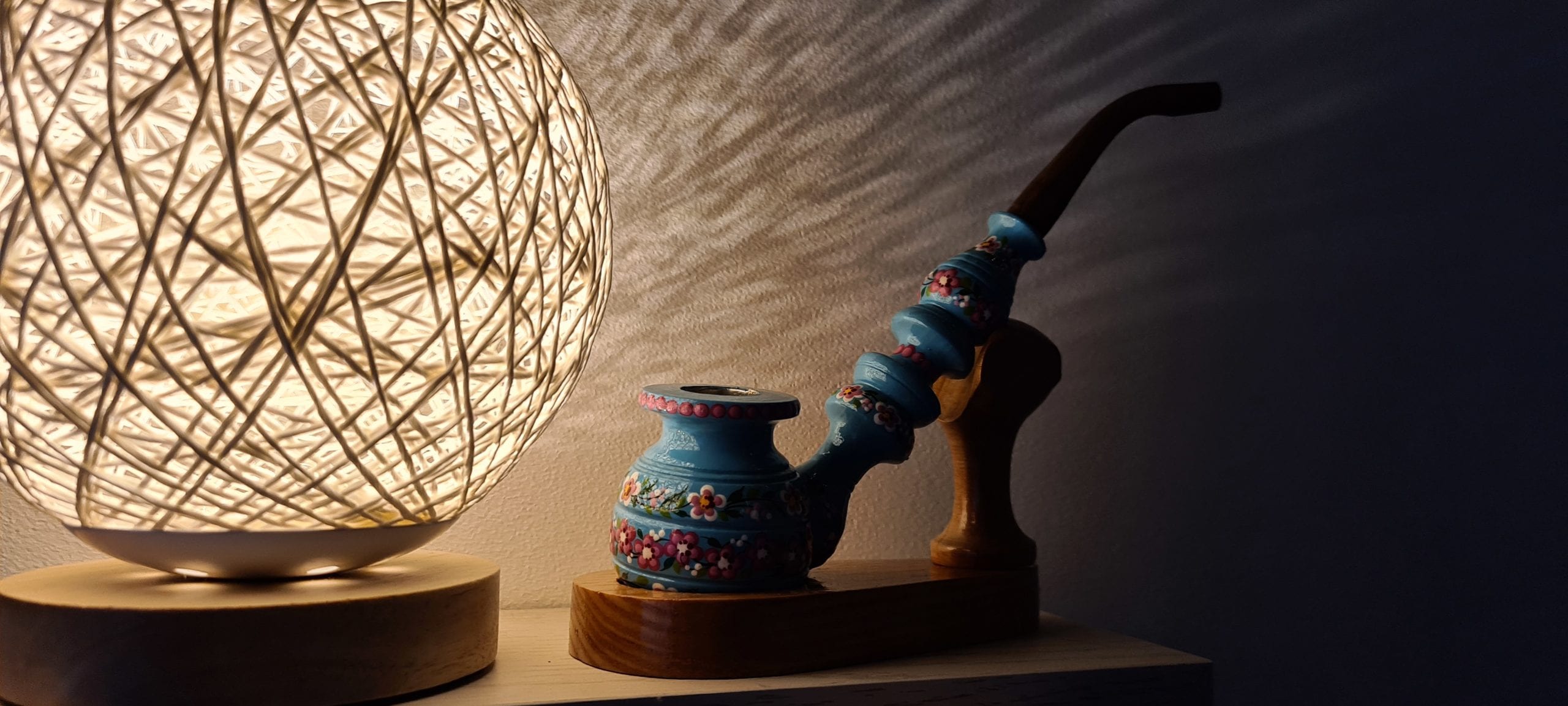 a decorative pipe on a wooden stand next to a lamp that looks like a ball of yarn