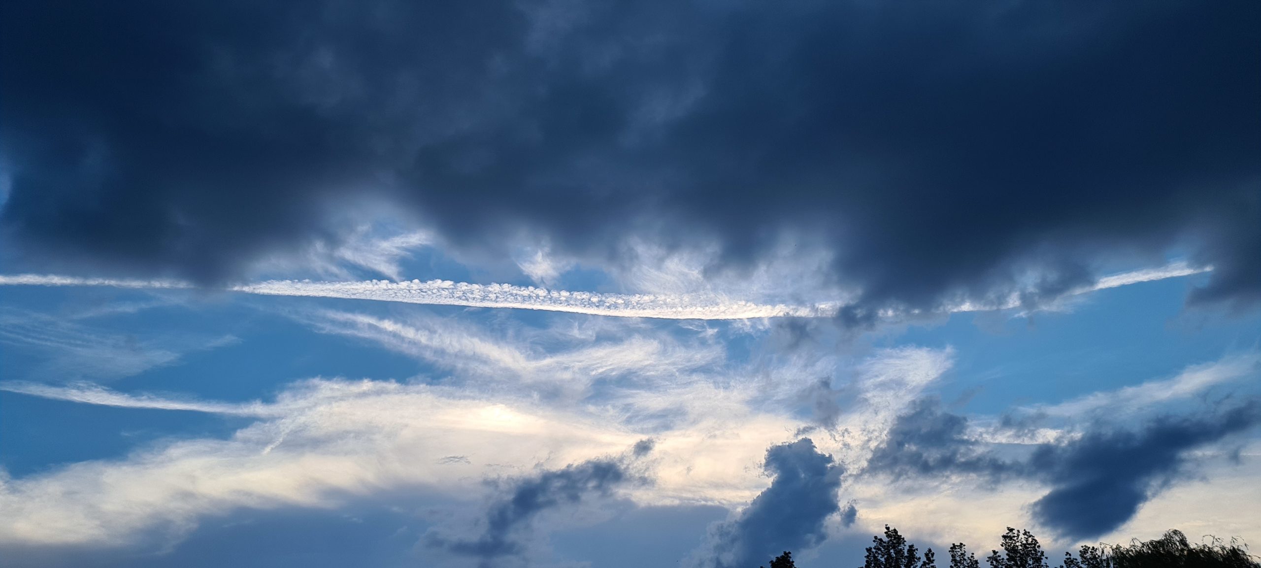 a blue sky with clouds and airplane trails