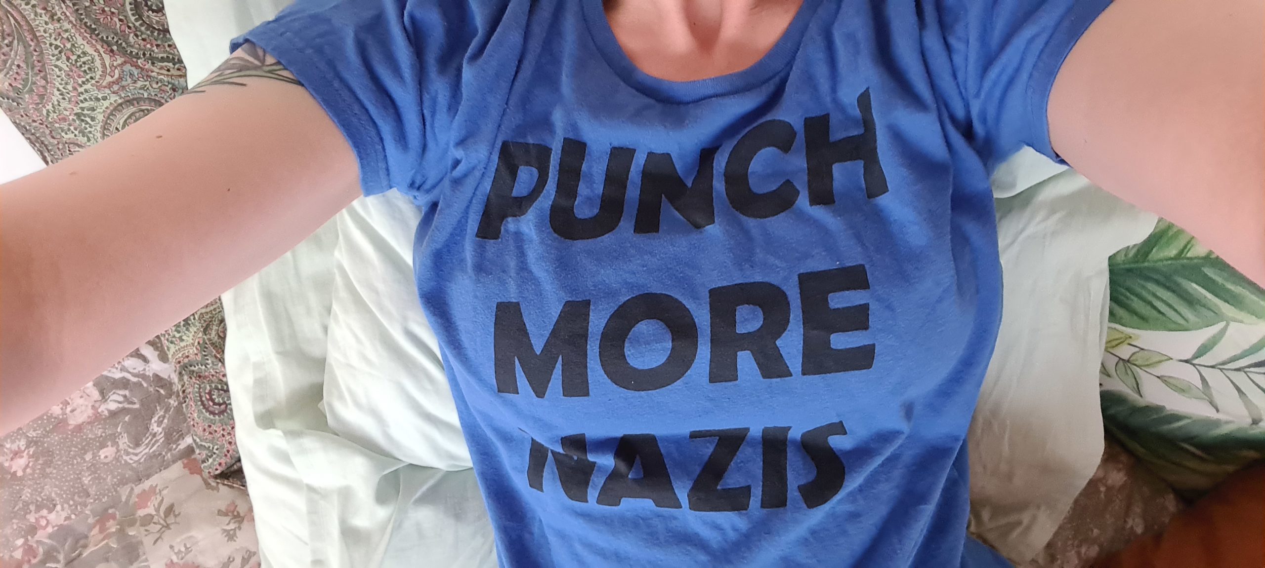 torso of white lady wearing a tshirt that says "Punch More Nazis"