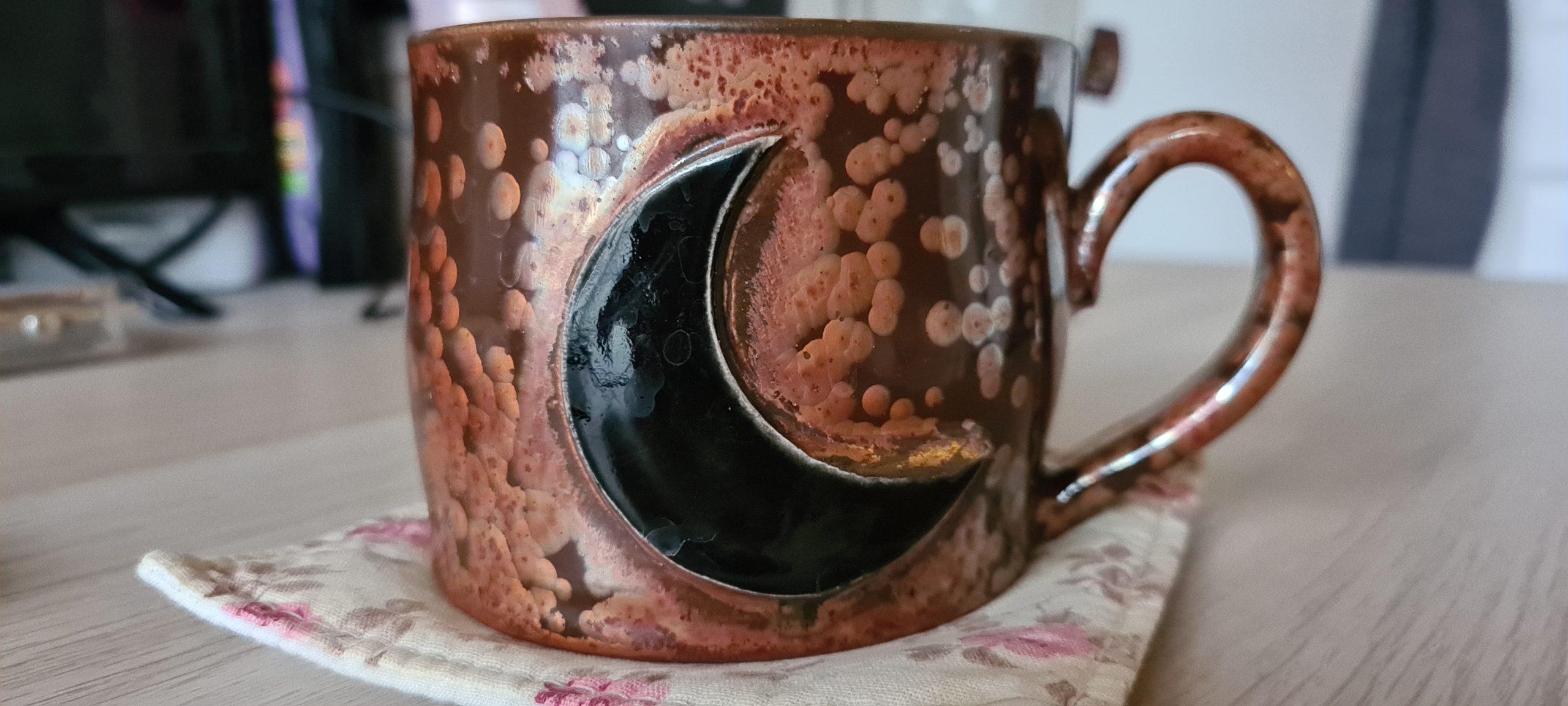 a large mug painted to look like waterstained tin with a black crecent moon on it