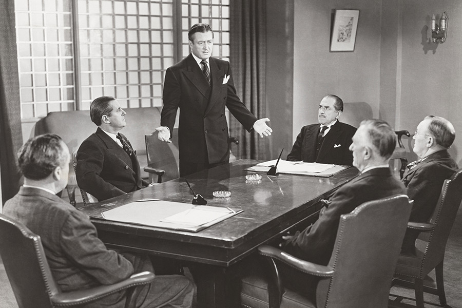black and white photo of white dudes around a board room table