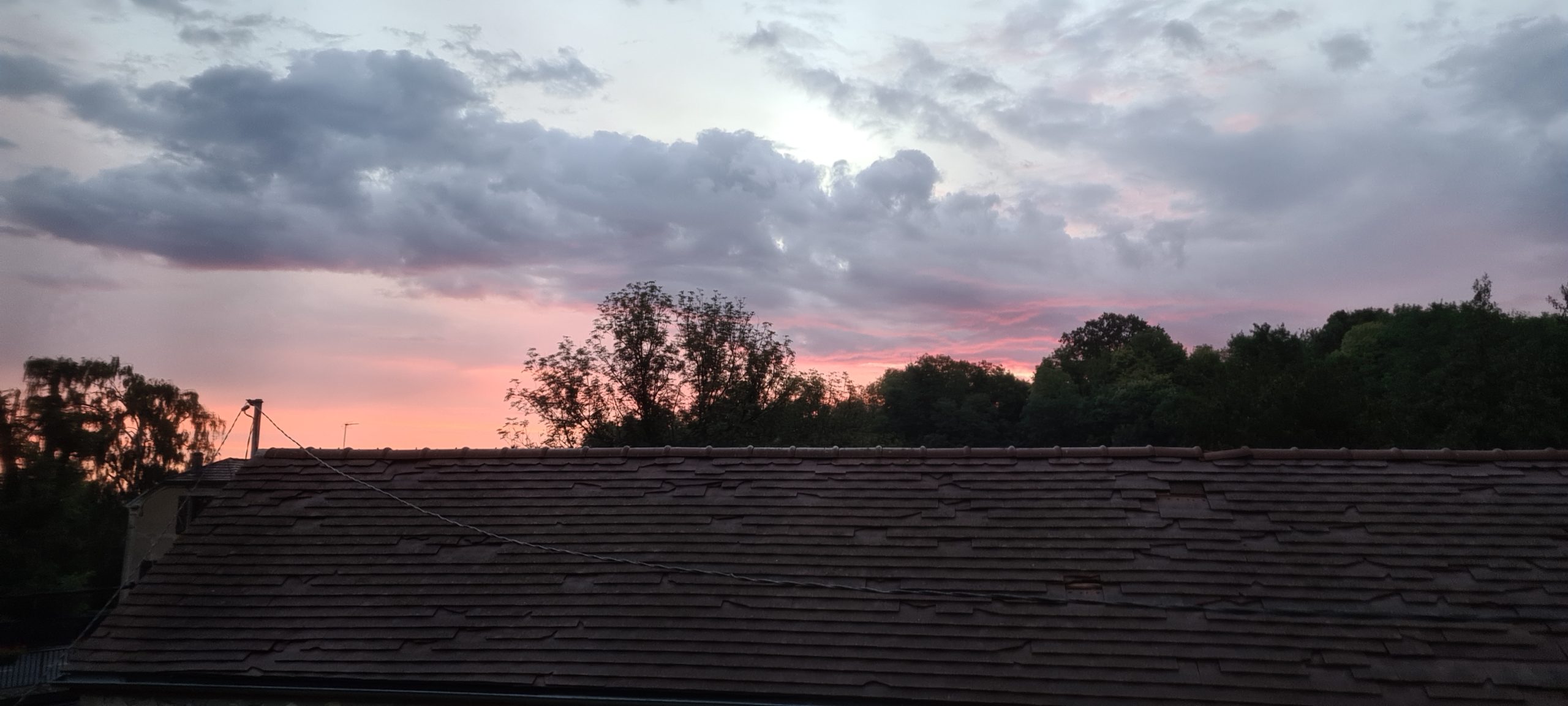 sunrise behind a roof and trees