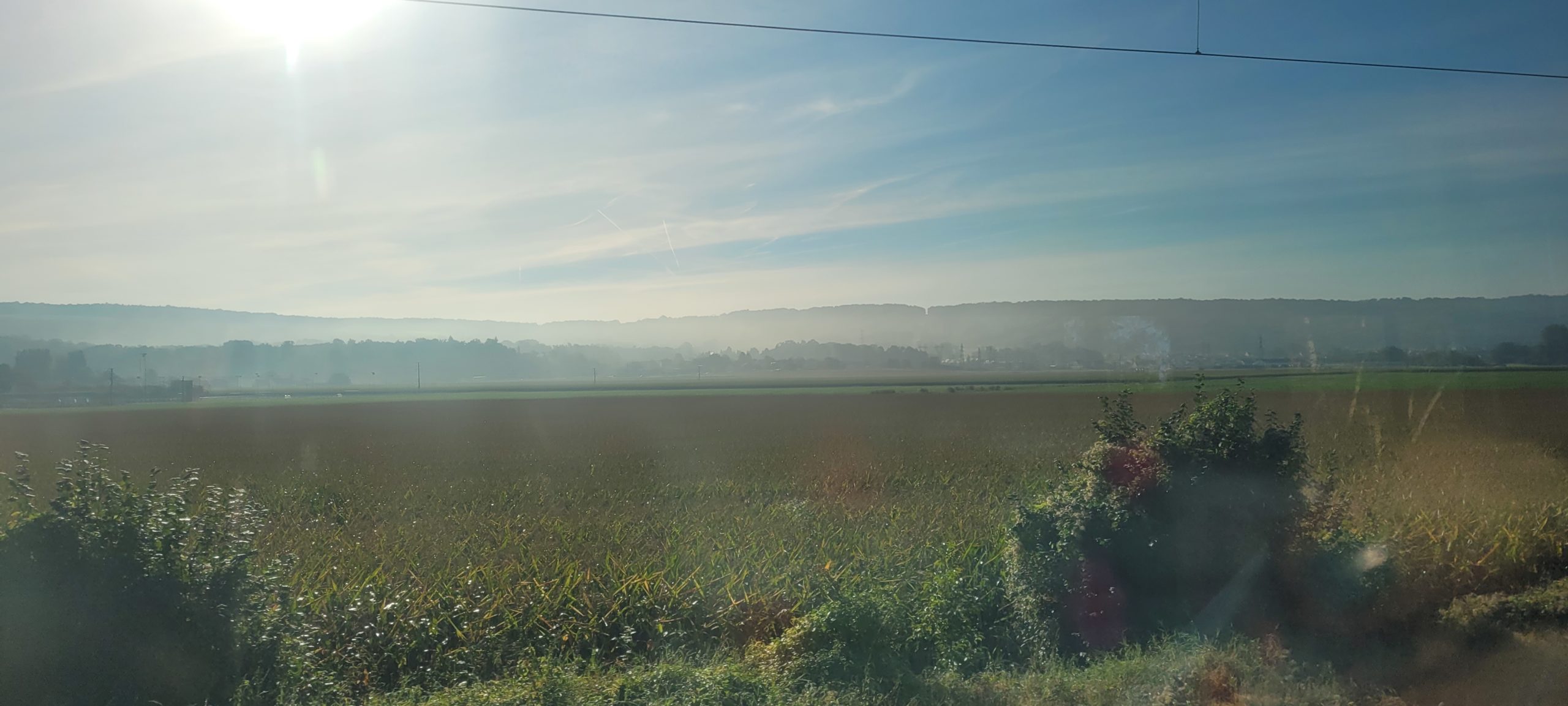 farm fields with hills in the back ground, slightly misty moring view from a train