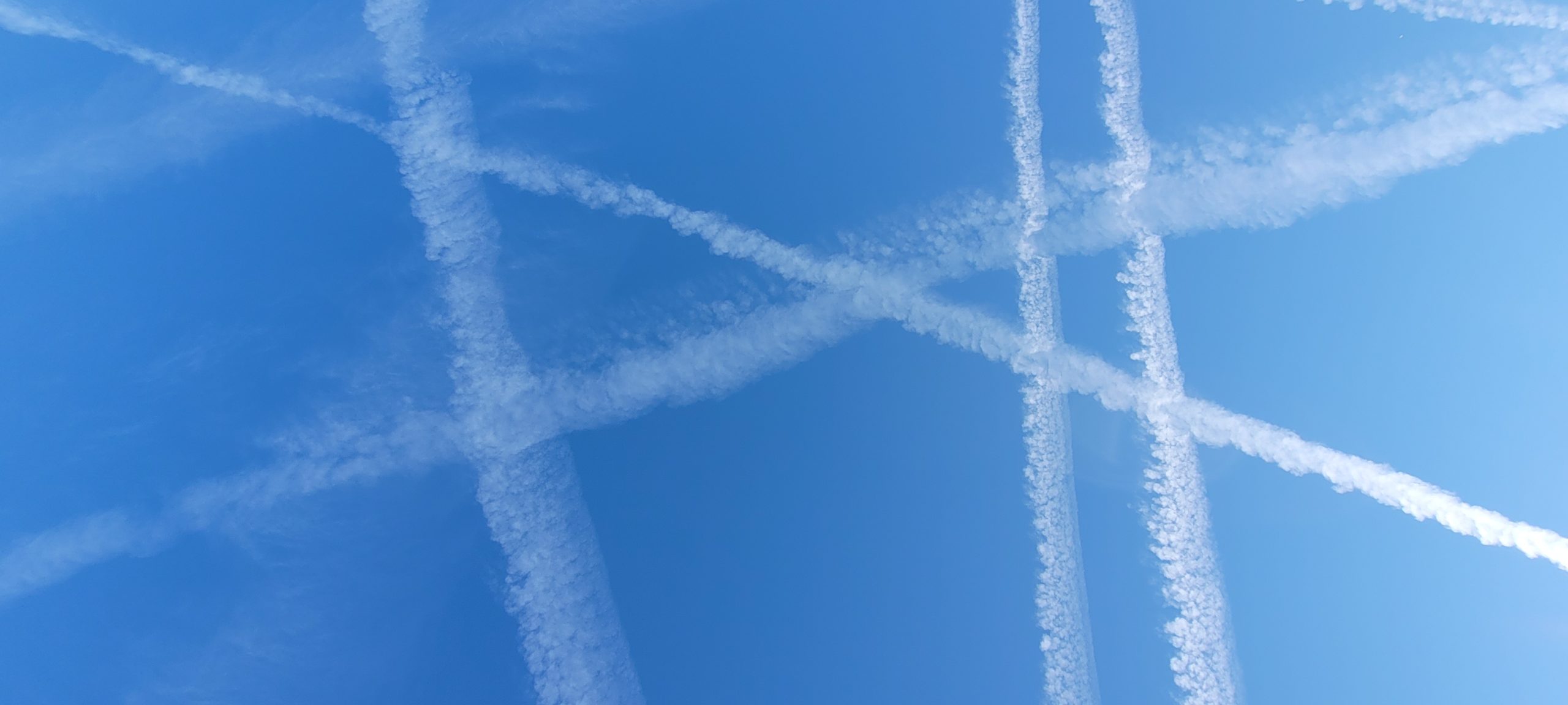 a blue sky criss-crossed with white airplain trails