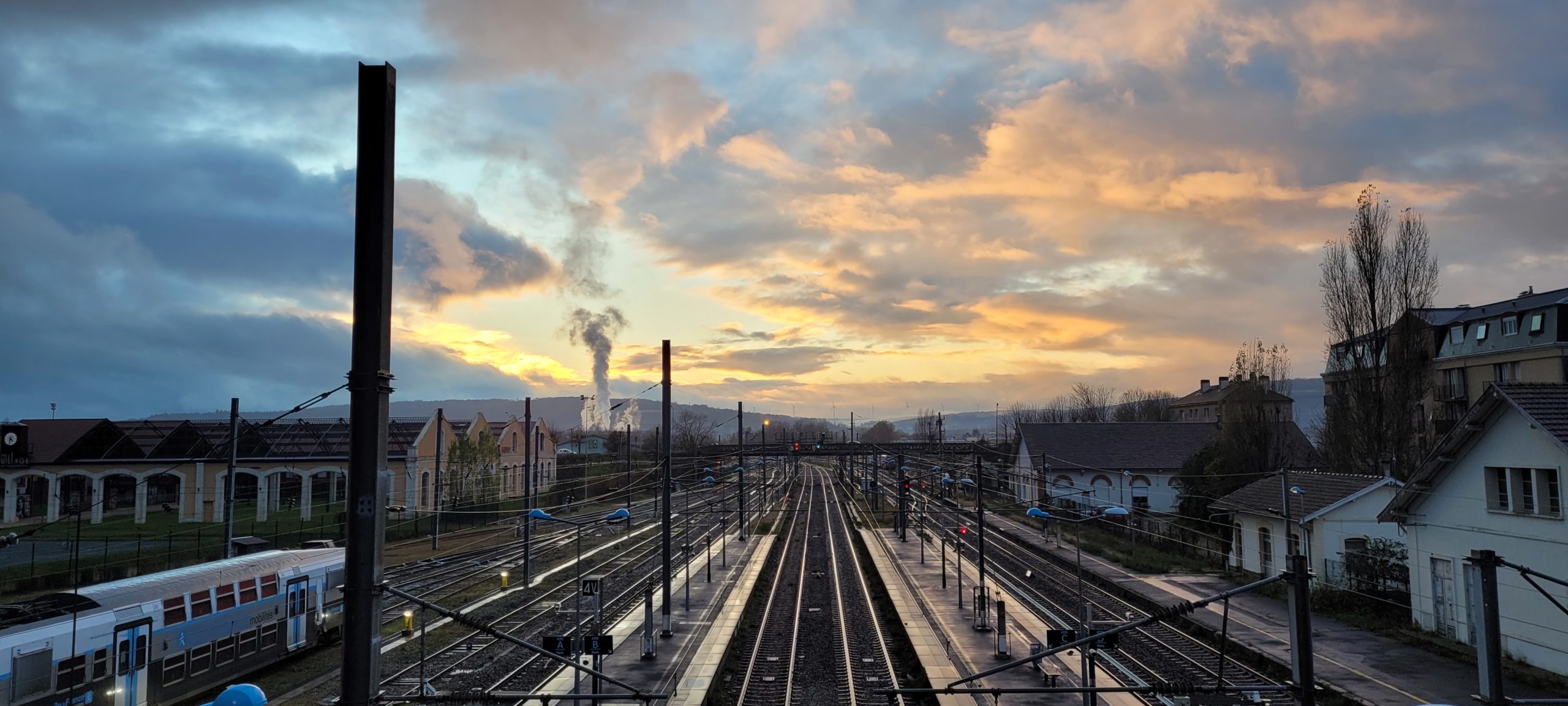 train tracks below a sunset with clouds, wet from rain