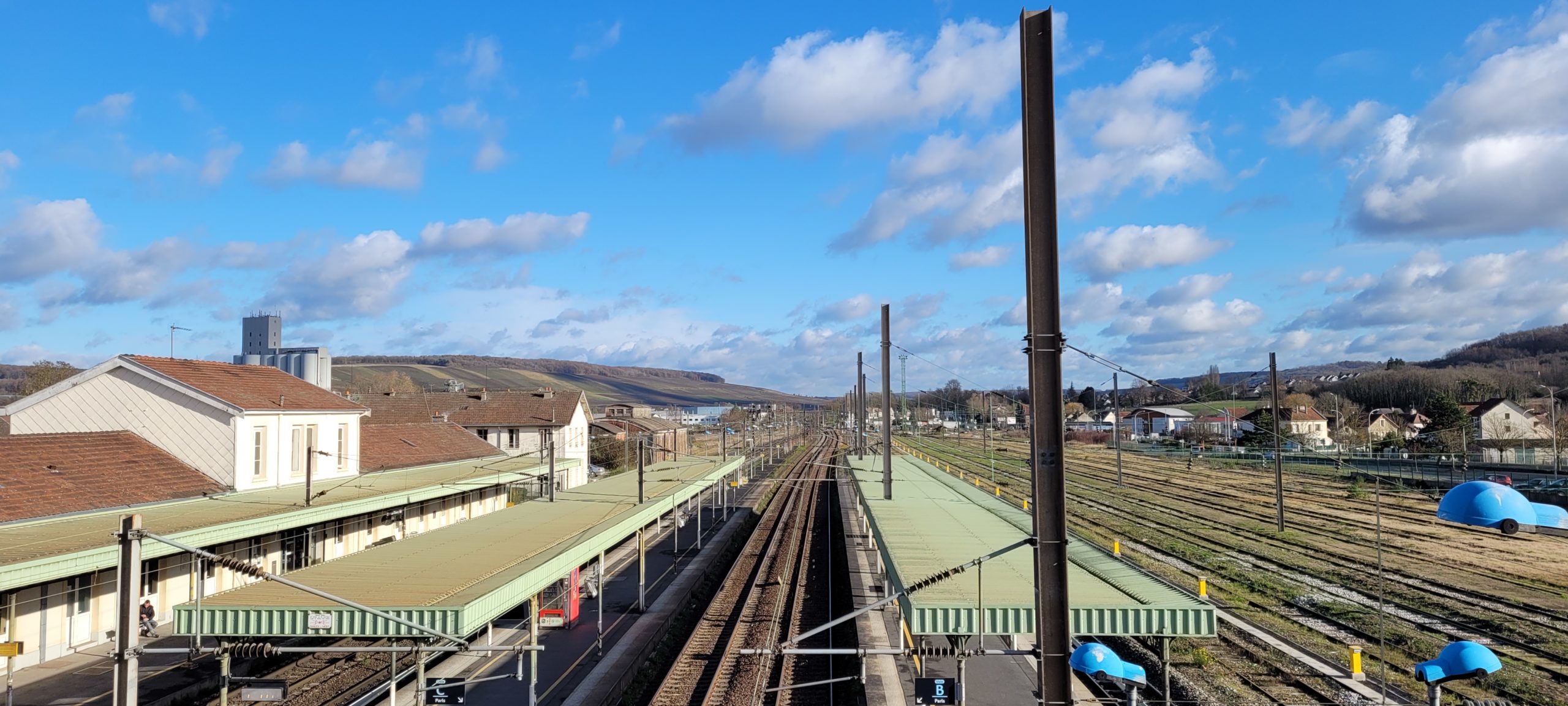 a train station below a blue sky with clouds