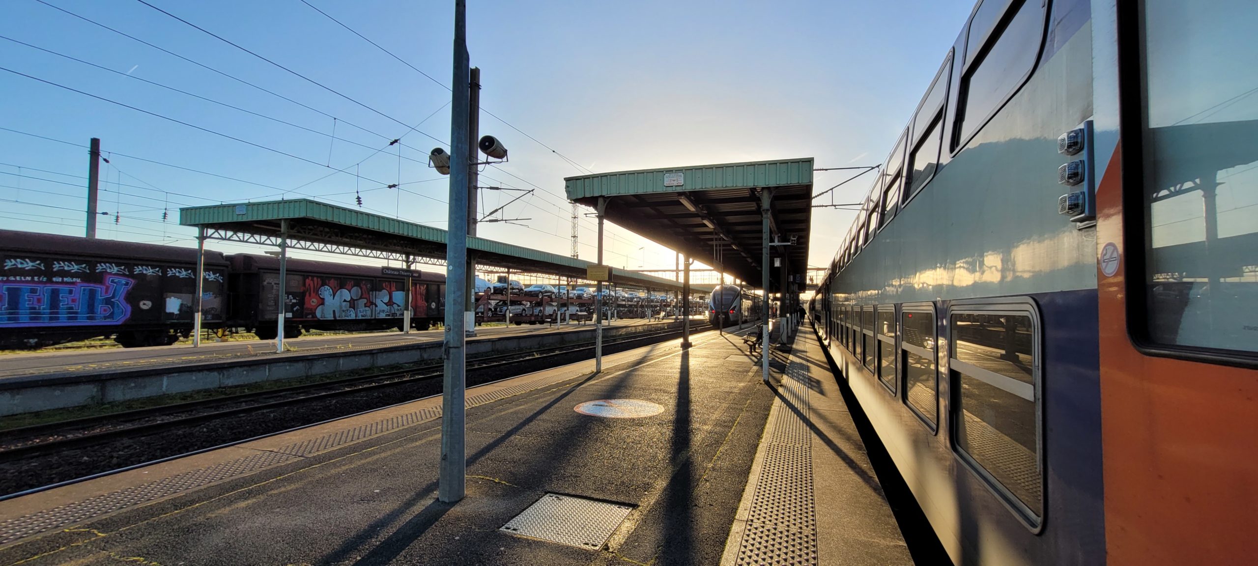 a train station platform with setting sun casting shadows