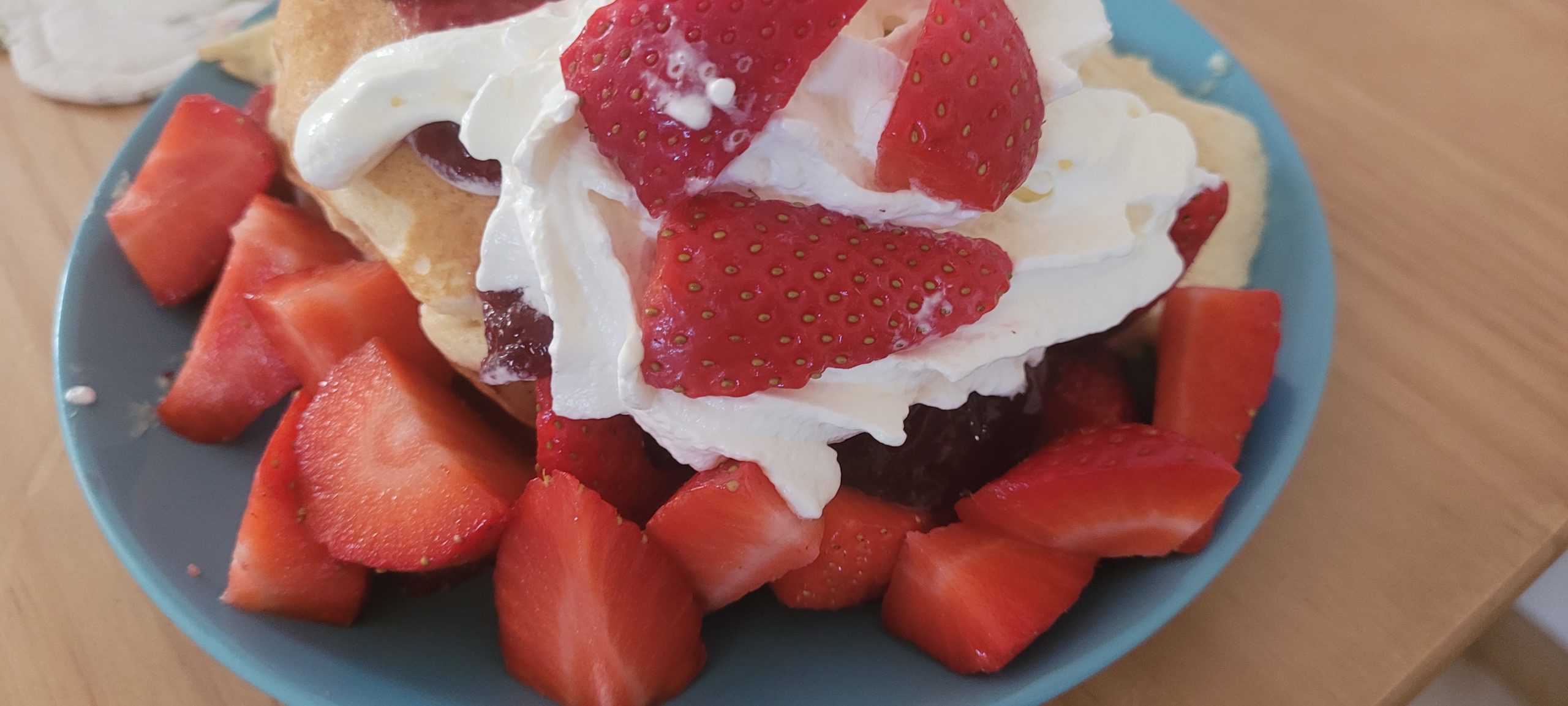 a plate of pancakes that is mostly strawberries and whipped cream