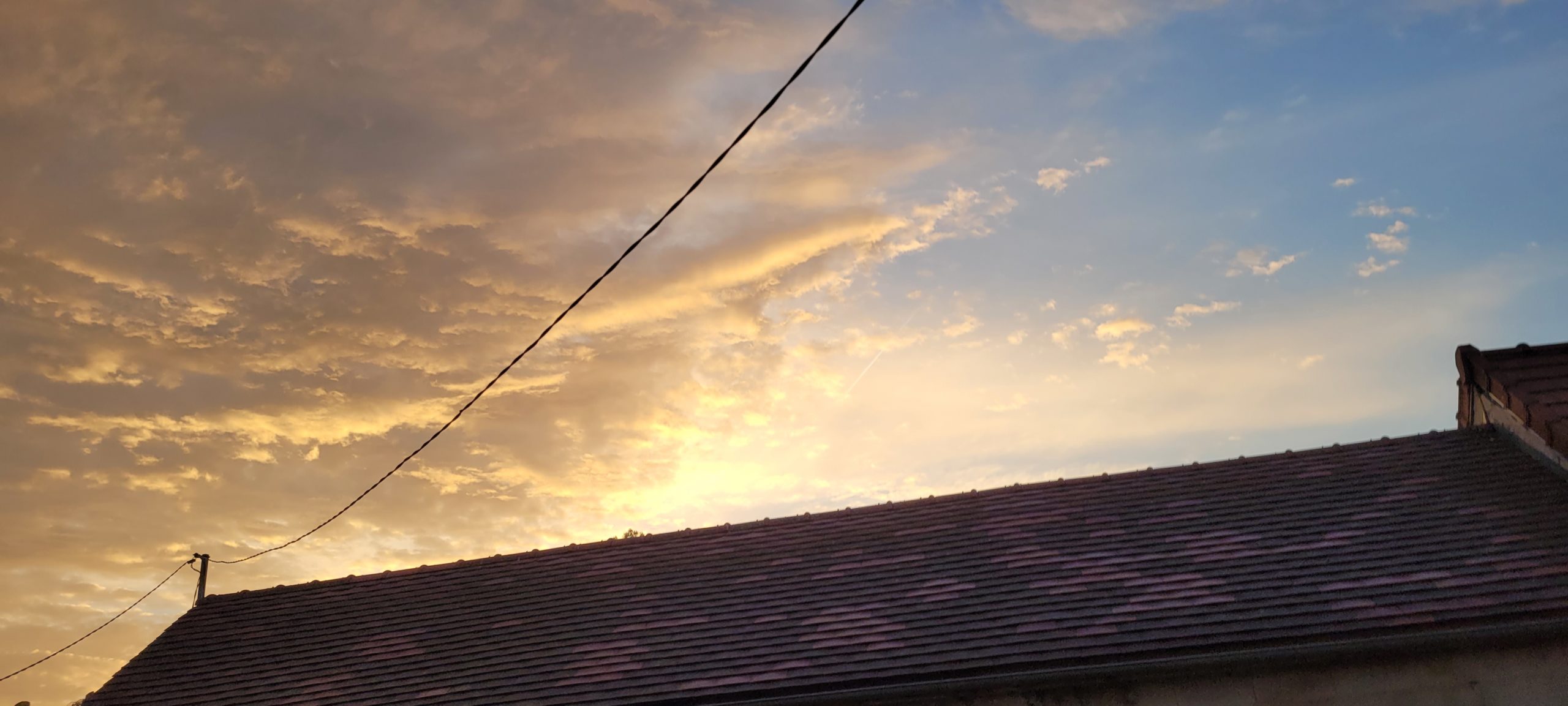 sunrise behind some clouds and a rooftop