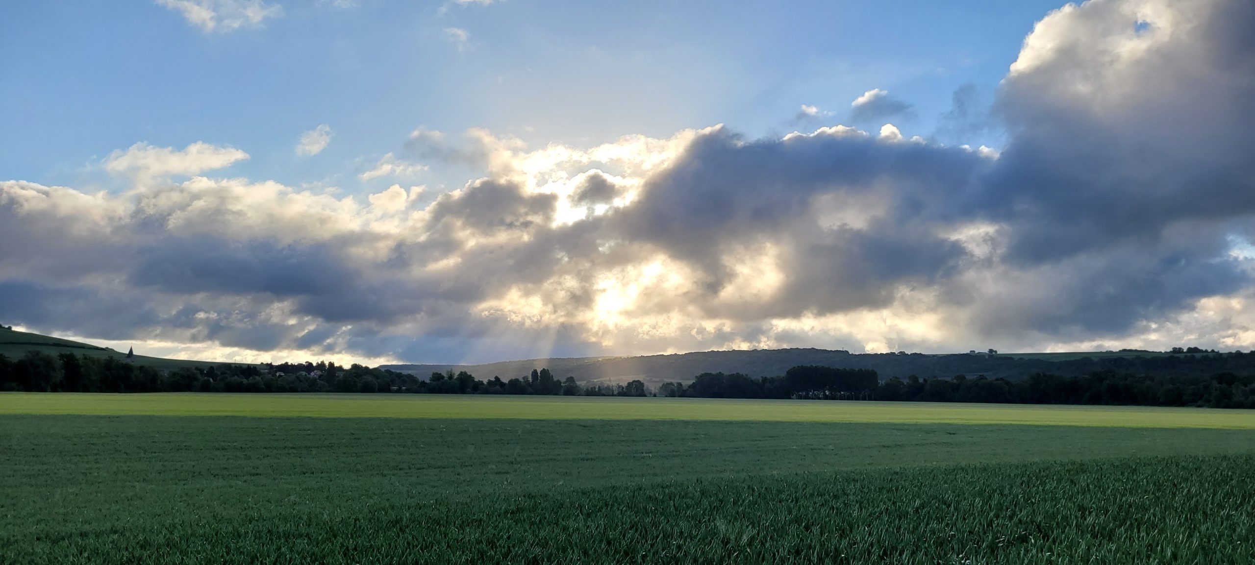 sunrise behind white clouds over farm fields