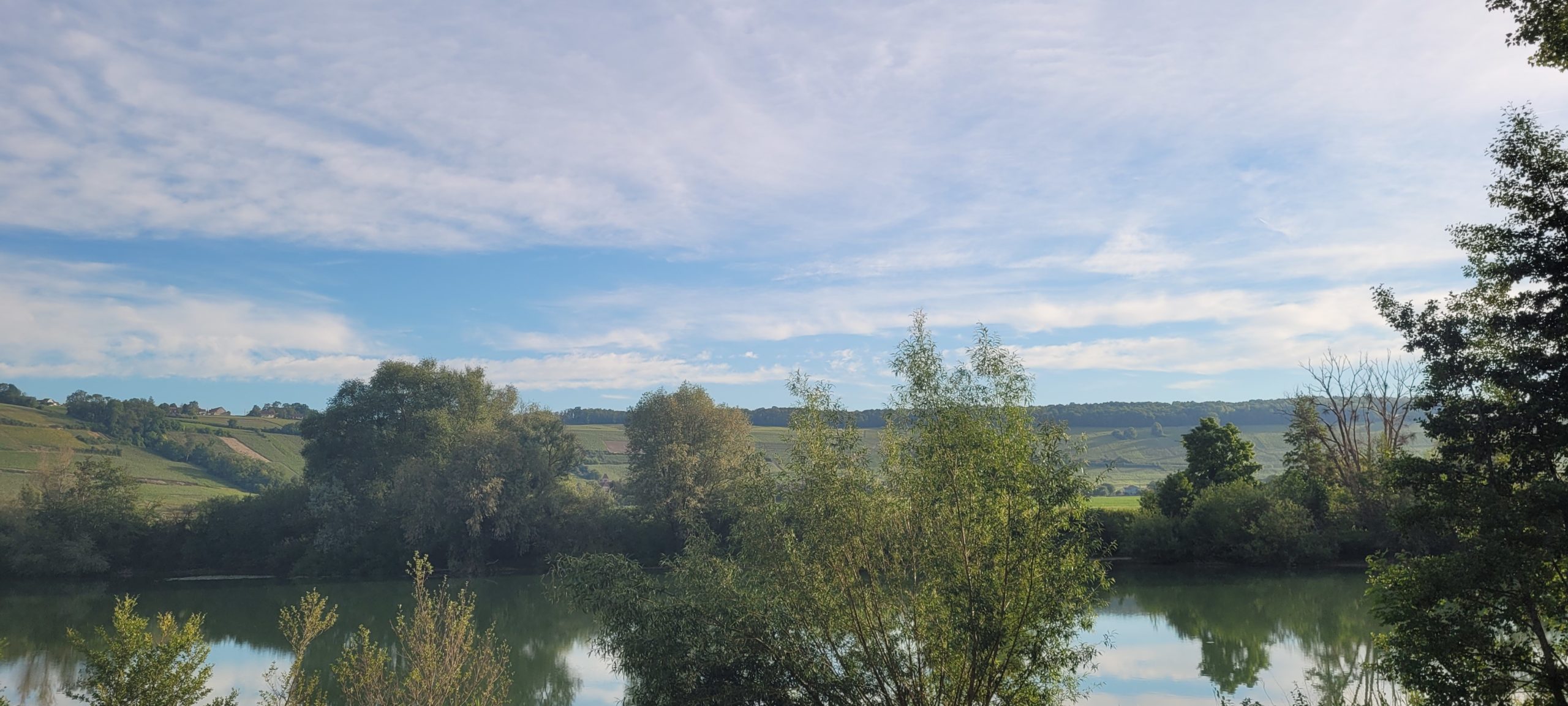 river below a blue sky with thin white clouds