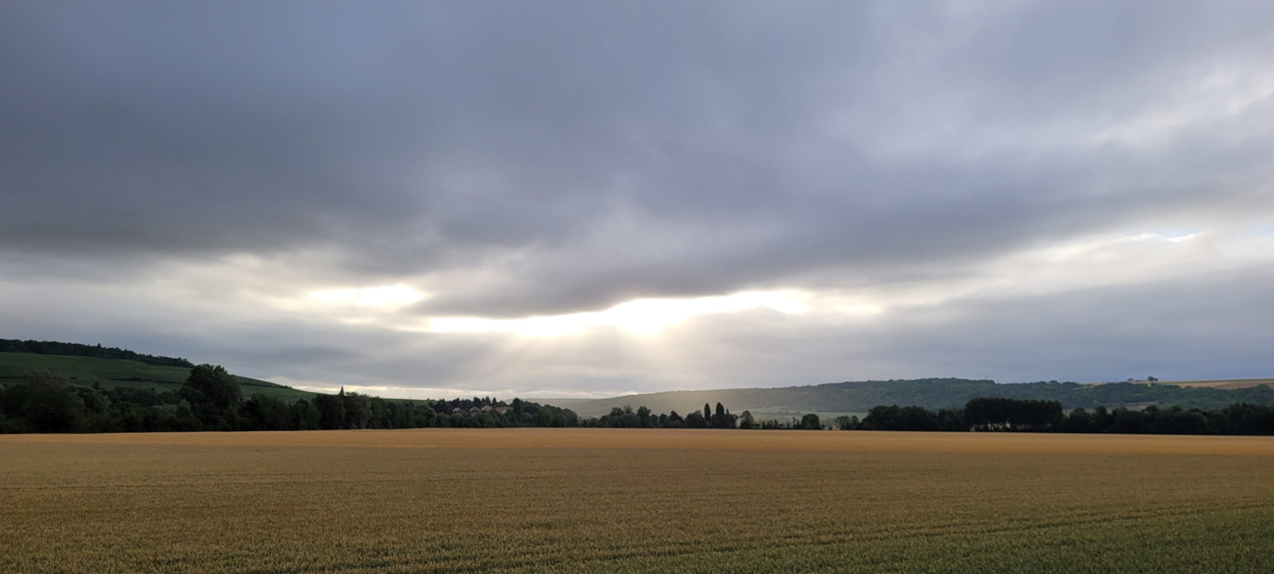 sunrise behind thick clouds over farmland