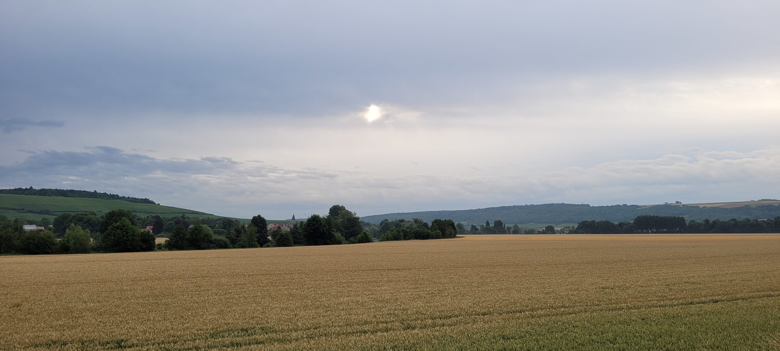 sunrise behind clouds above farm fields