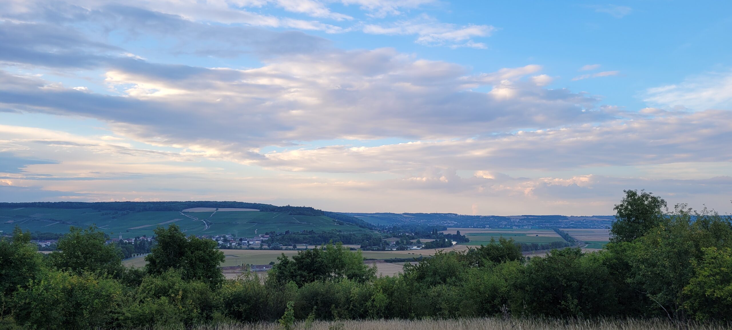 white clouds tinted pink in a light blue sky at sunset over french countryside