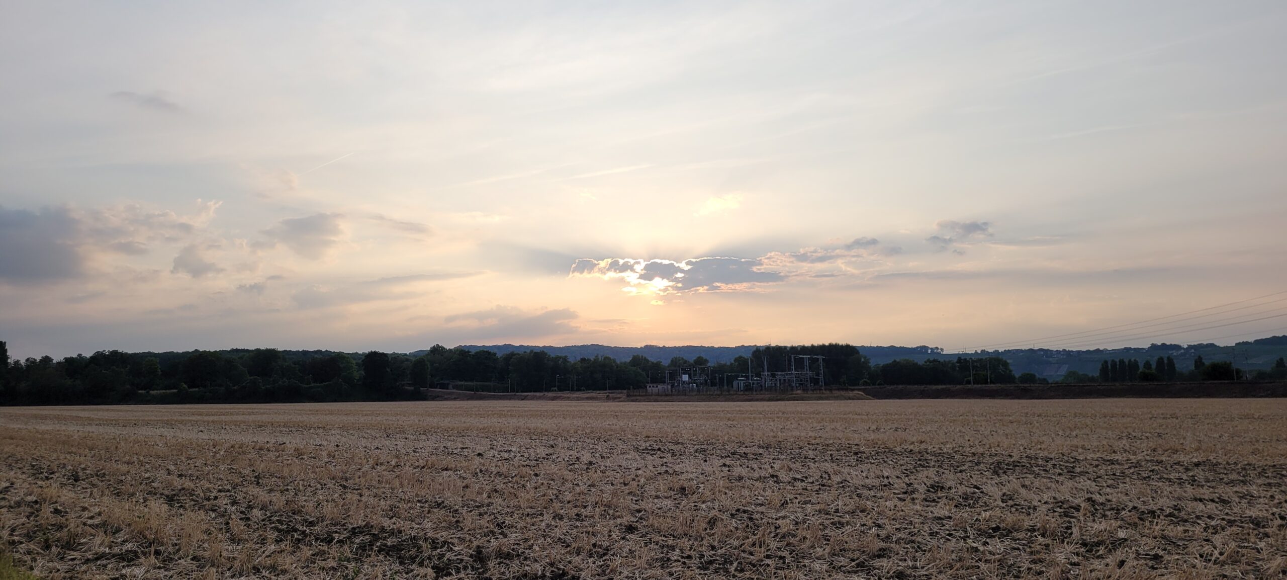 sunrise in a hazy sky over farm fields