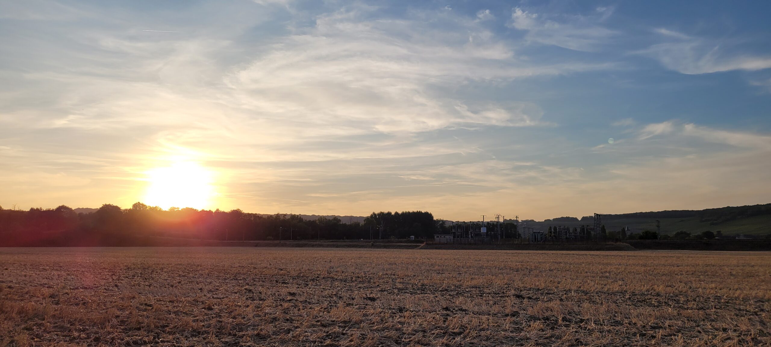 sunset behind a hill and farm fields