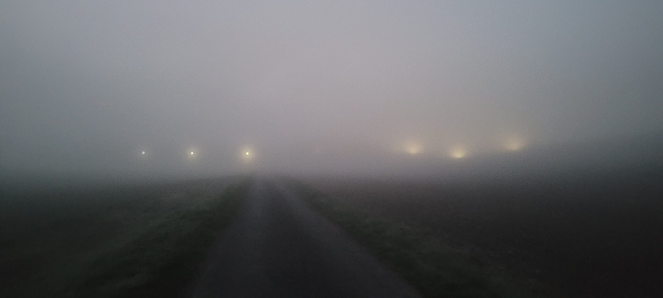 spotlights on a building obscured by fog before sunrise