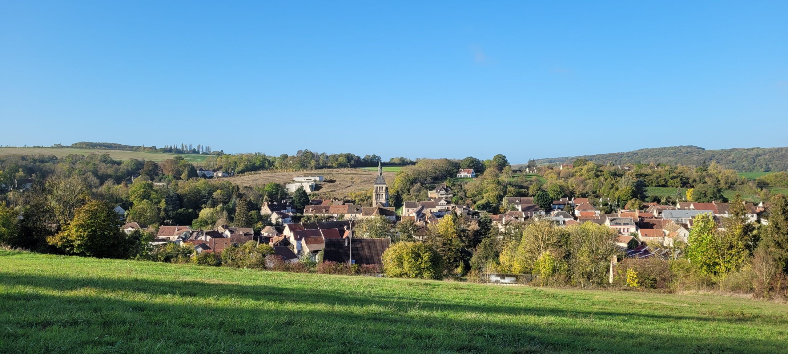 a small French village in a valley under blue sky