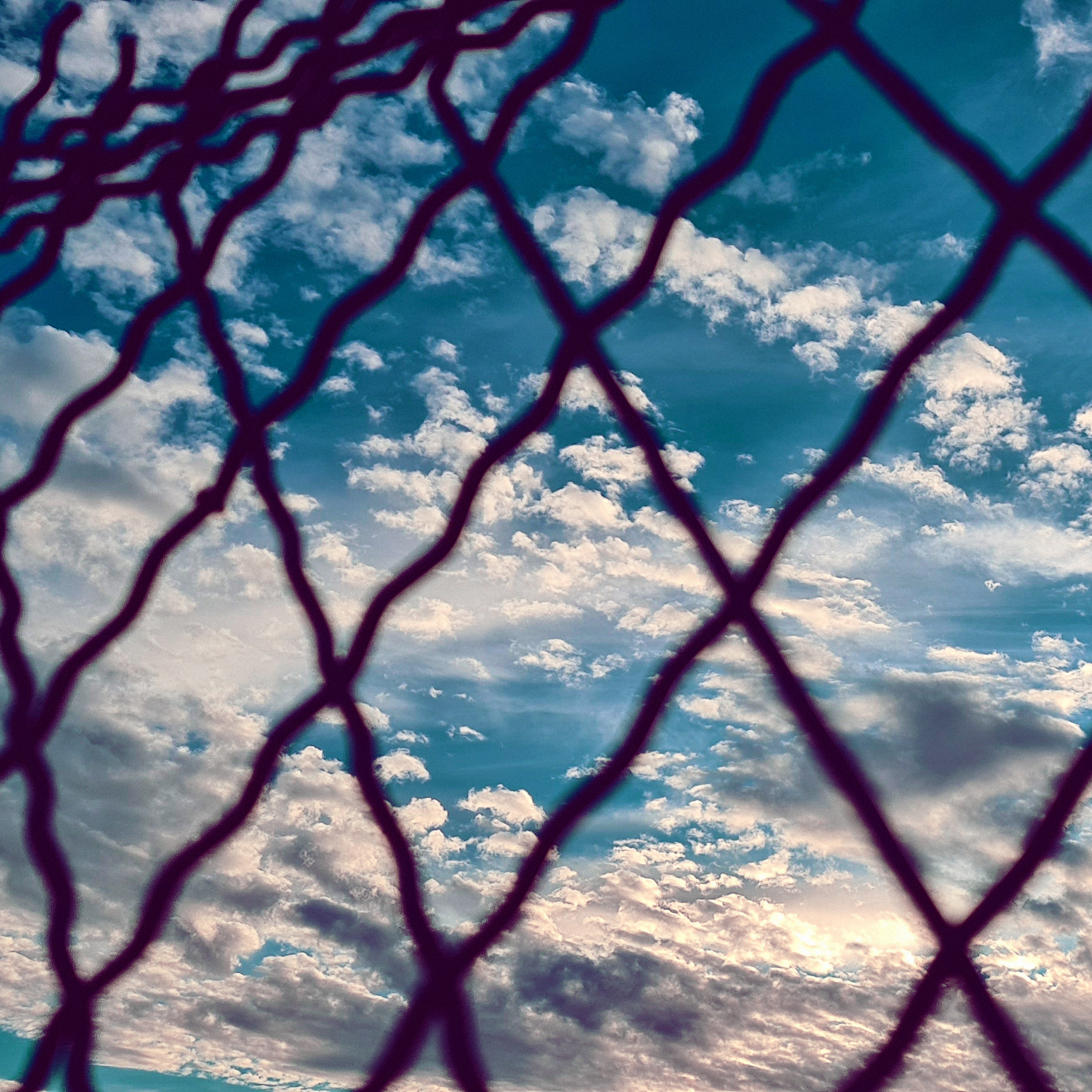 a chain link fence in front of a cloudy sky